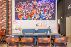 A conference room with a long table and chairs, a large mural on the wall, and a brick wall on one side. - Yijiayi Holiday Hotel (Jinghong)