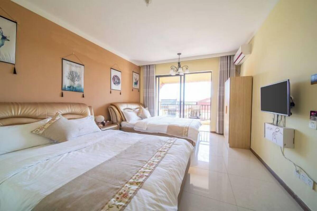 A hotel room with two beds, a TV, and a balcony with a view.