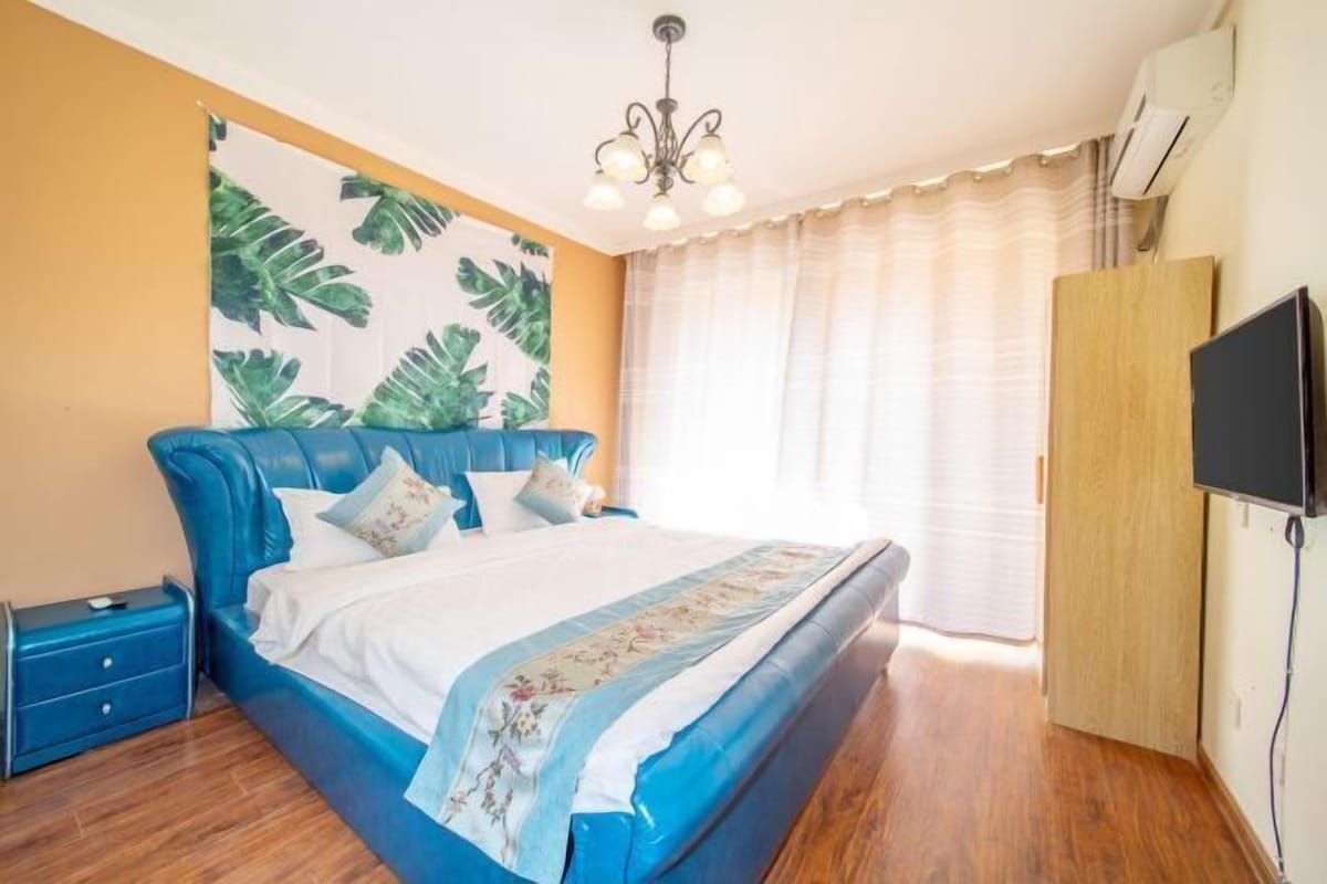 A bedroom with a large bed, a nightstand, a TV, and a wardrobe.