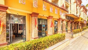 Fachada de hotel con varios balcones y una fila de tiendas en la planta baja.
