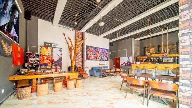 Un restaurante espacioso con techos altos, paredes de ladrillo visto y diversas opciones de asientos, incluidas mesas y sillas.