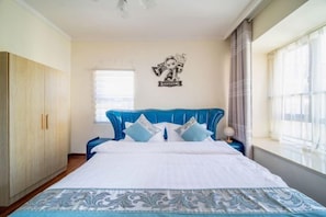 A bedroom with a bed, a wardrobe, a window with curtains, and a wall decoration. - Yijiayi Holiday Hotel (Jinghong)