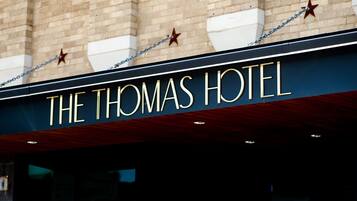 The exterior of The Thomas Hotel with a prominent sign and star decorations.