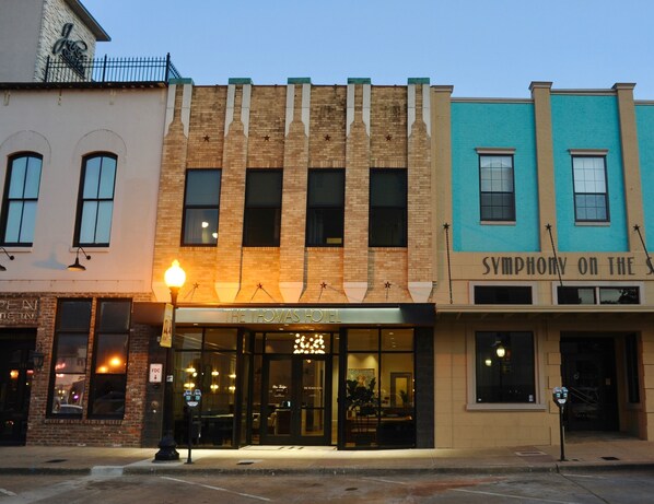 Una hilera de edificios con un restaurante llamado "The Thomas Hotel" en el centro, que presenta una fachada moderna y ventanas amplias.