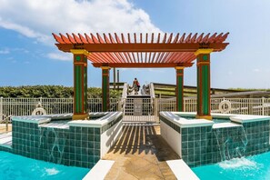 Un espace piscine doté d’une allée couverte, d’une tour de surveillance pour les sauveteurs et offrant une vue sur le paysage environnant.