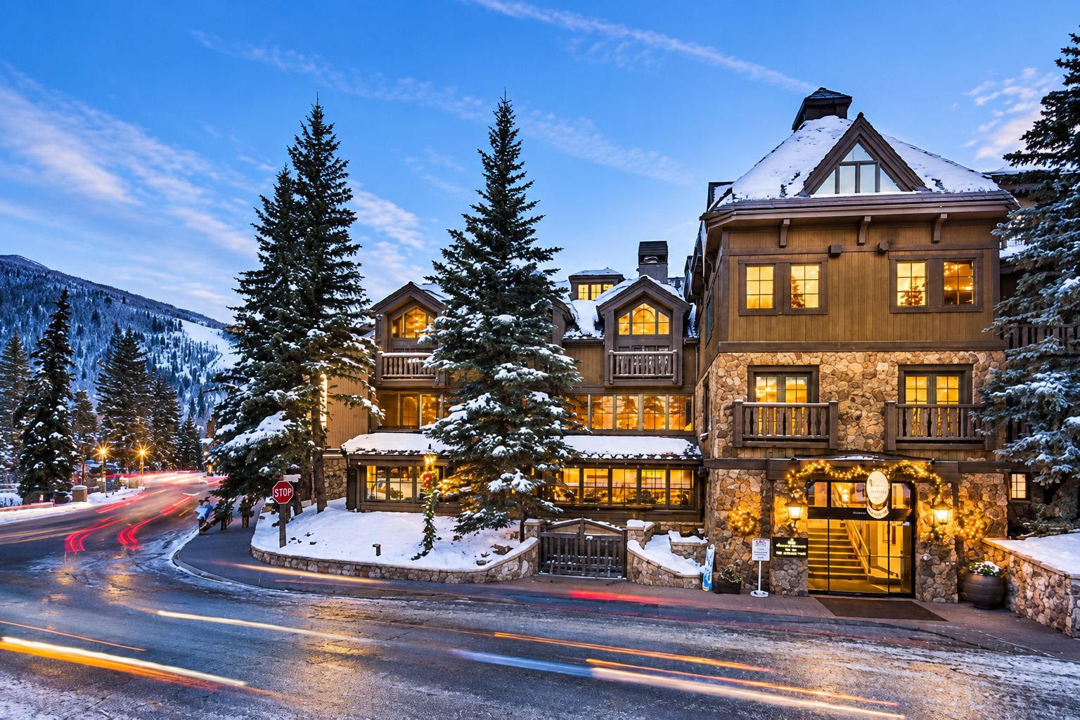 A large, multi-story lodge with a stone facade, wooden balconies, and snow-covered surroundings.