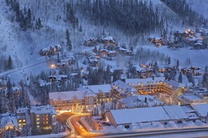 Ein schneebedecktes Resort mit mehreren Gebäuden, einer Seilbahn und einer Serpentinenstraße.