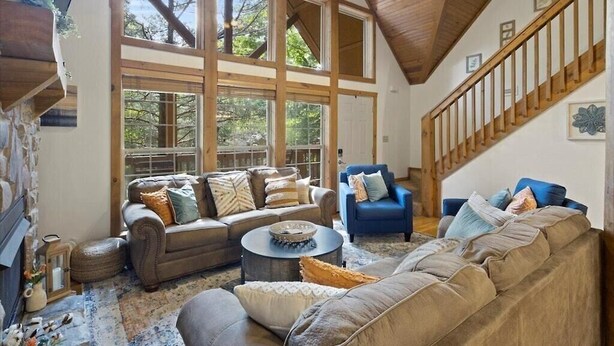 Un salón espacioso con techo alto, ventanas amplias, una escalera y chimenea.