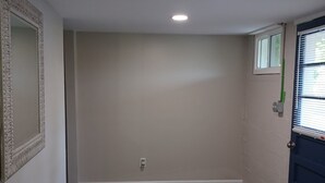 A hallway with a patterned wooden floor, a blue door, and a small window with blinds. - Spacious and Serene Basement (McMinnville)