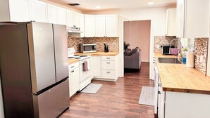 A modern kitchen with white cabinets, a stainless steel refrigerator, a microwave, and a stove.