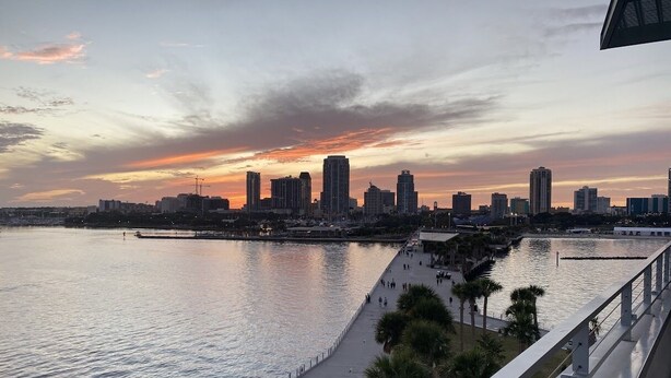 A waterfront cityscape with a pedestrian walkway and a view of the skyline.