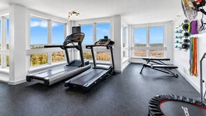 Un gimnasio con cintas de correr, una bicicleta estática y un trampolín.