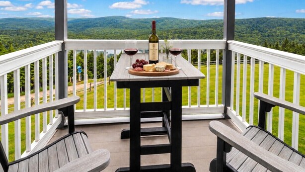 Una terraza de madera con una mesa lista para comer, con vistas a un paisaje verde.