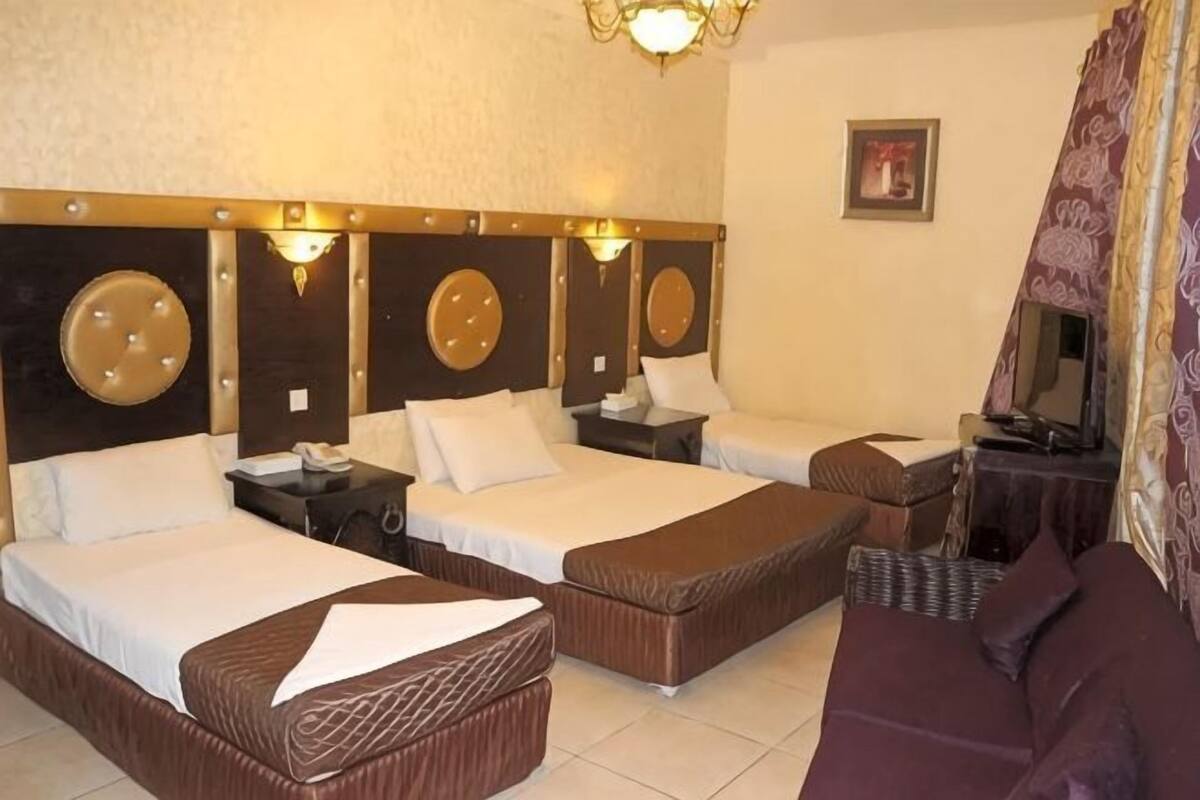 Une chambre d’hôtel avec deux lits, un canapé, une télévision et une petite table.