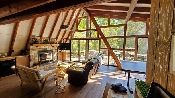 Un chalet confortable avec une cheminée en pierre, des meubles en bois et de grandes fenêtres donnant sur le paysage extérieur.
