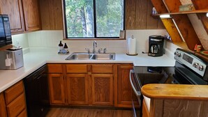 Une cuisine avec des meubles de rangement en bois, un évier à deux bacs, une machine à café et un grille-pain.