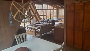 Un intérieur de chalet chaleureux avec un coin repas, un canapé et une table de ping-pong.