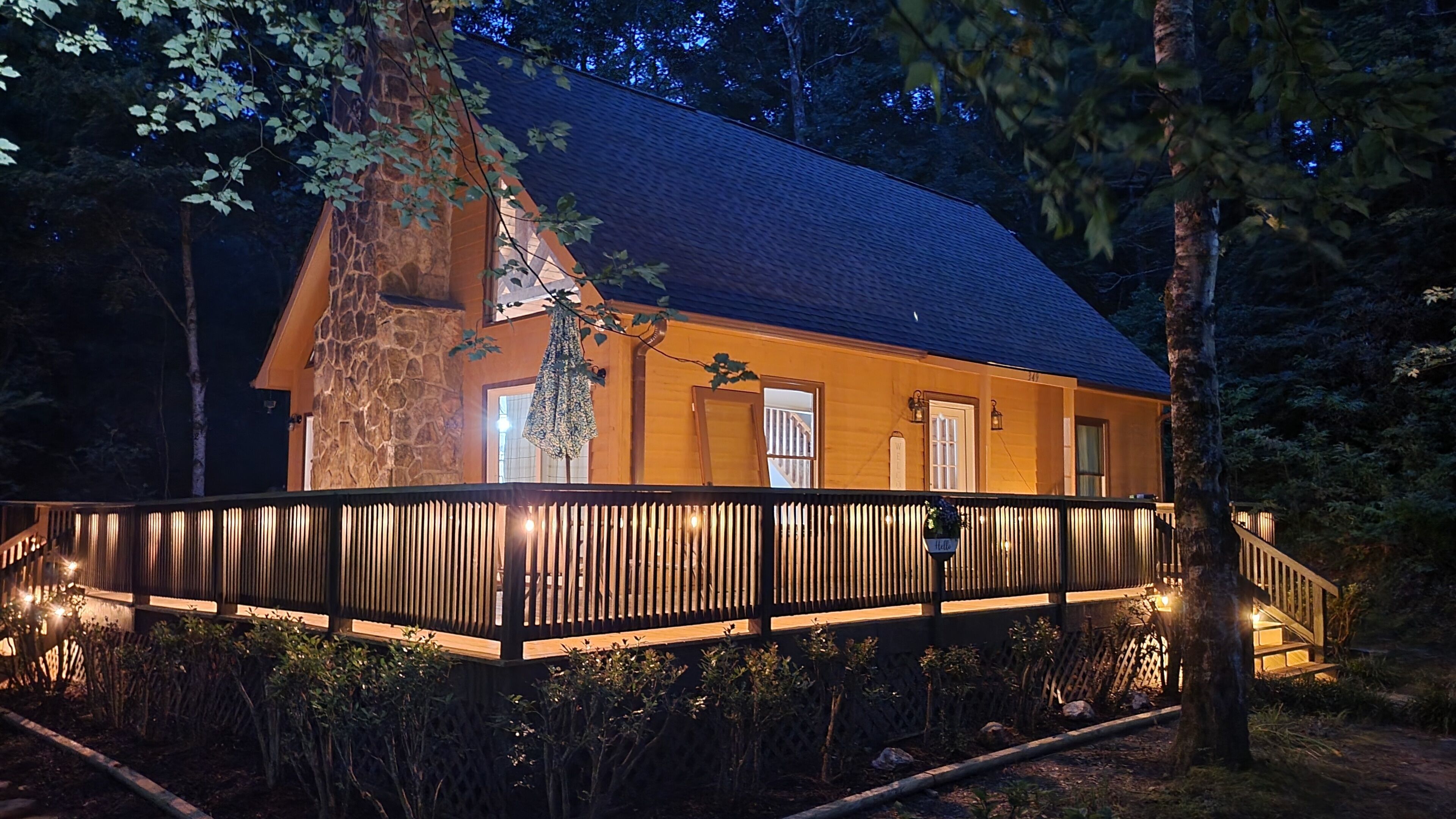 A wooden cabin with a stone facade, a balcony with railings, and a staircase leading to the entrance.