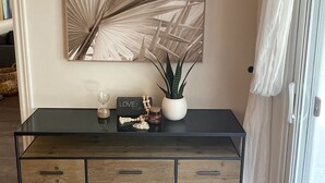 Une console moderne agrémentée d’un grand miroir, d’une plante en pot et d’objets décoratifs.