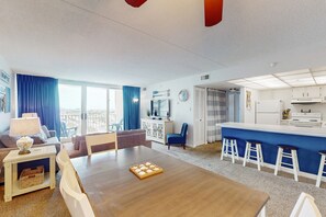 Enjoy a spacious living room with a dining table, bar stools, and a kitchenette, offering a city view.