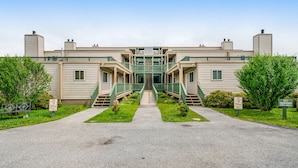 A modern building with a central staircase leading to a balcony, surrounded by greenery and marked with 'No Parking' signs. - Gorgeous condo with hot tub, heated indoor pool, fireplace, balcony, & fast WiFi (Beech Mountain)