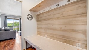 A room with a wooden wall, a white bench, a grey sofa, and a window with curtains. - Gorgeous condo with hot tub, heated indoor pool, fireplace, balcony, & fast WiFi (Beech Mountain)