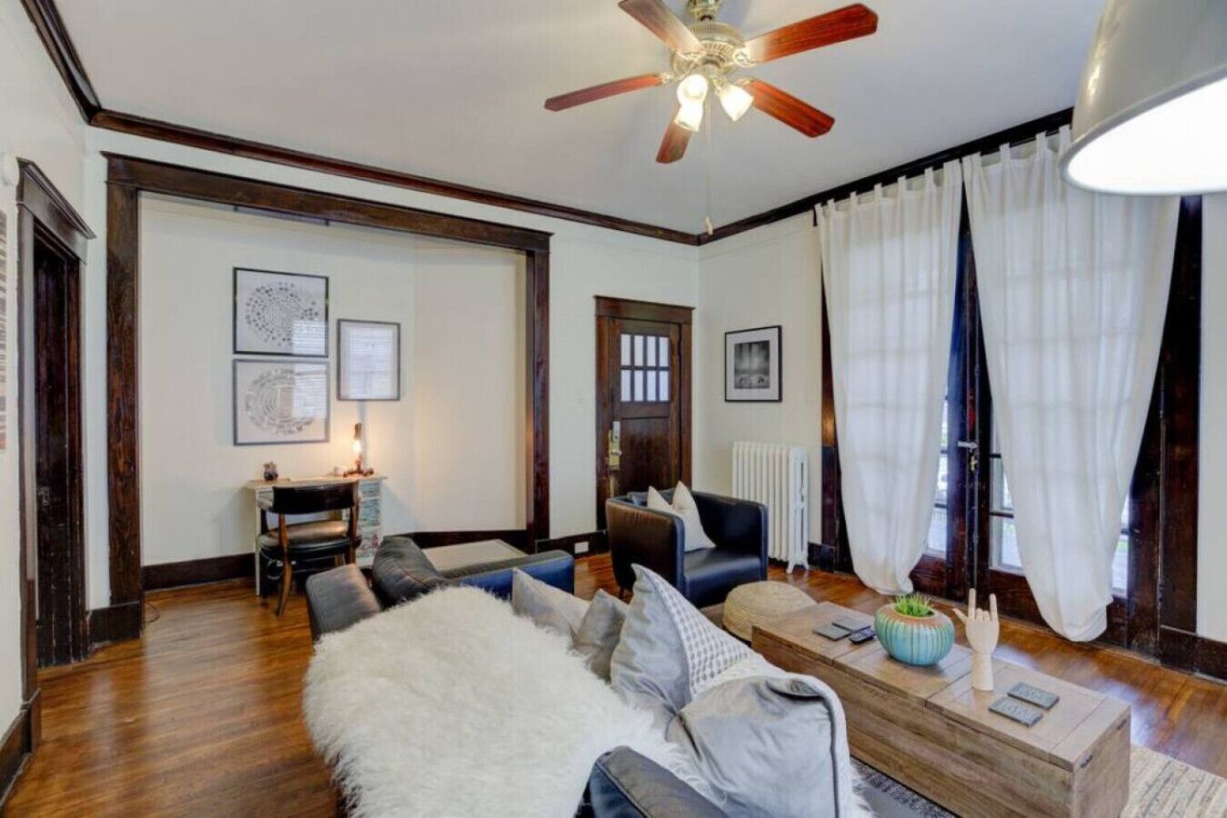 A living room with a ceiling fan, a fireplace, a sofa, a coffee table, and a window with curtains.