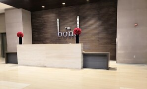A reception desk with a modern design, a wooden slatted wall in the background, and two red flowers on either side.