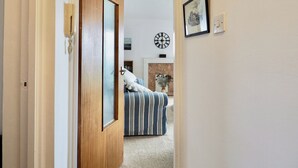 A hallway leading to a bedroom with a bed, a clock, and a framed picture on the wall. - 2 bedroom accommodation in Bexhill On Sea (Bexhill On Sea)