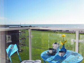 A balcony with a clear view of the sea, a table with a vase and teapots, and a chair. - 2 bedroom accommodation in Bexhill On Sea (Bexhill On Sea)
