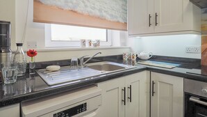 A modern kitchen with a large window, white cabinets, and a stainless steel sink. - 2 bedroom accommodation in Bexhill On Sea (Bexhill On Sea)
