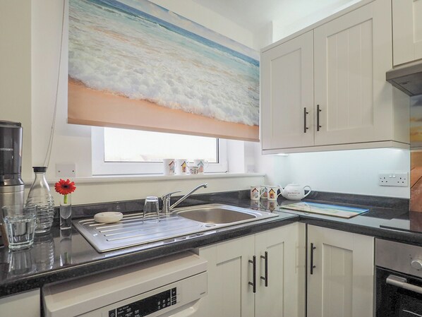 A modern kitchen with a large window, white cabinets, and a stainless steel sink. - 2 bedroom accommodation in Bexhill On Sea (Bexhill On Sea)