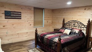 Een kamer met houten lambrisering, een bed, een klein tafeltje en een vlag aan de muur.