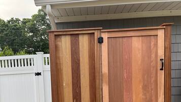 A wooden outdoor storage cabinet with a hinged door and a small step for access.