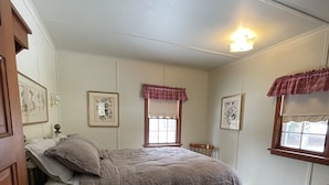 Una camera da letto con un letto, una cassettiera in legno, un comodino e una finestra con tenda.