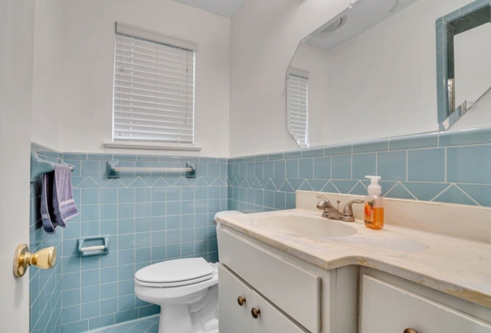 A bathroom with a toilet, sink, and mirror.