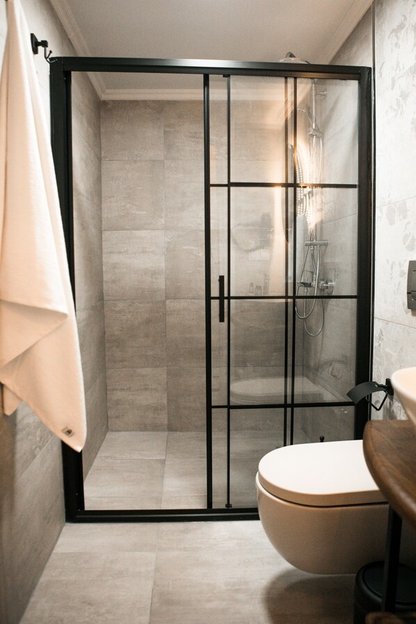 A modern bathroom with a glass-enclosed shower, a toilet, and a towel hanging on a rack. - Molo Urla (Urla)