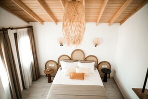 A bedroom with a wooden ceiling, a bed with multiple pillows, two bedside tables, and a hanging light fixture. - Molo Urla (Urla)