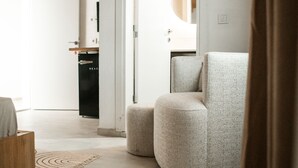 Una sala de estar moderna con un sillón redondo tapizado, una mesa de centro de madera y una cocina al fondo.