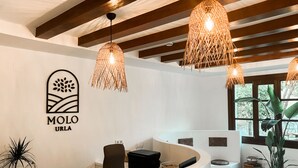 Un área de recepción con un mostrador curvo, un logotipo en la pared y lámparas de mimbre colgantes.