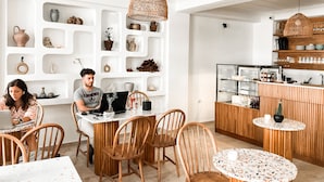 Un interior moderno con zona de comedor, sillas de madera, una mesa redonda y área de cocina con estanterías y vitrina.