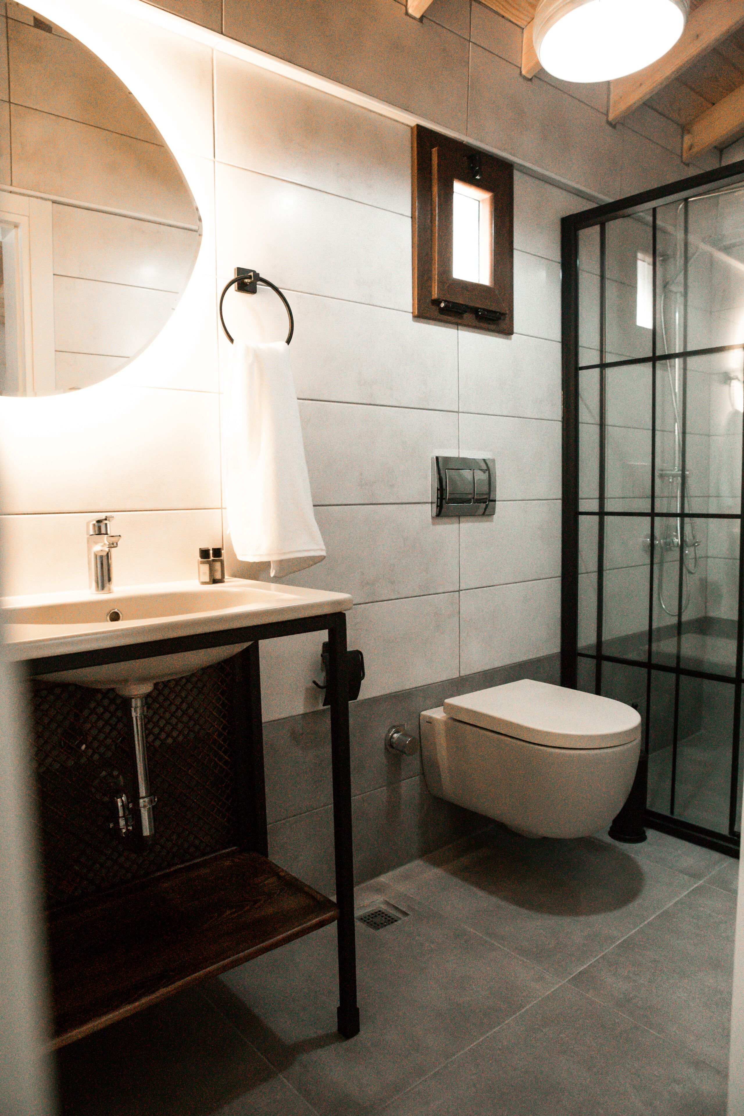 Ein modernes Badezimmer mit Waschbecken, Spiegel, Toilette und Duschkabine aus Glas.