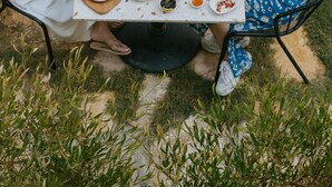 Un área de comedor al aire libre con una mesa lista para una comida, rodeada de sillas y un césped.
