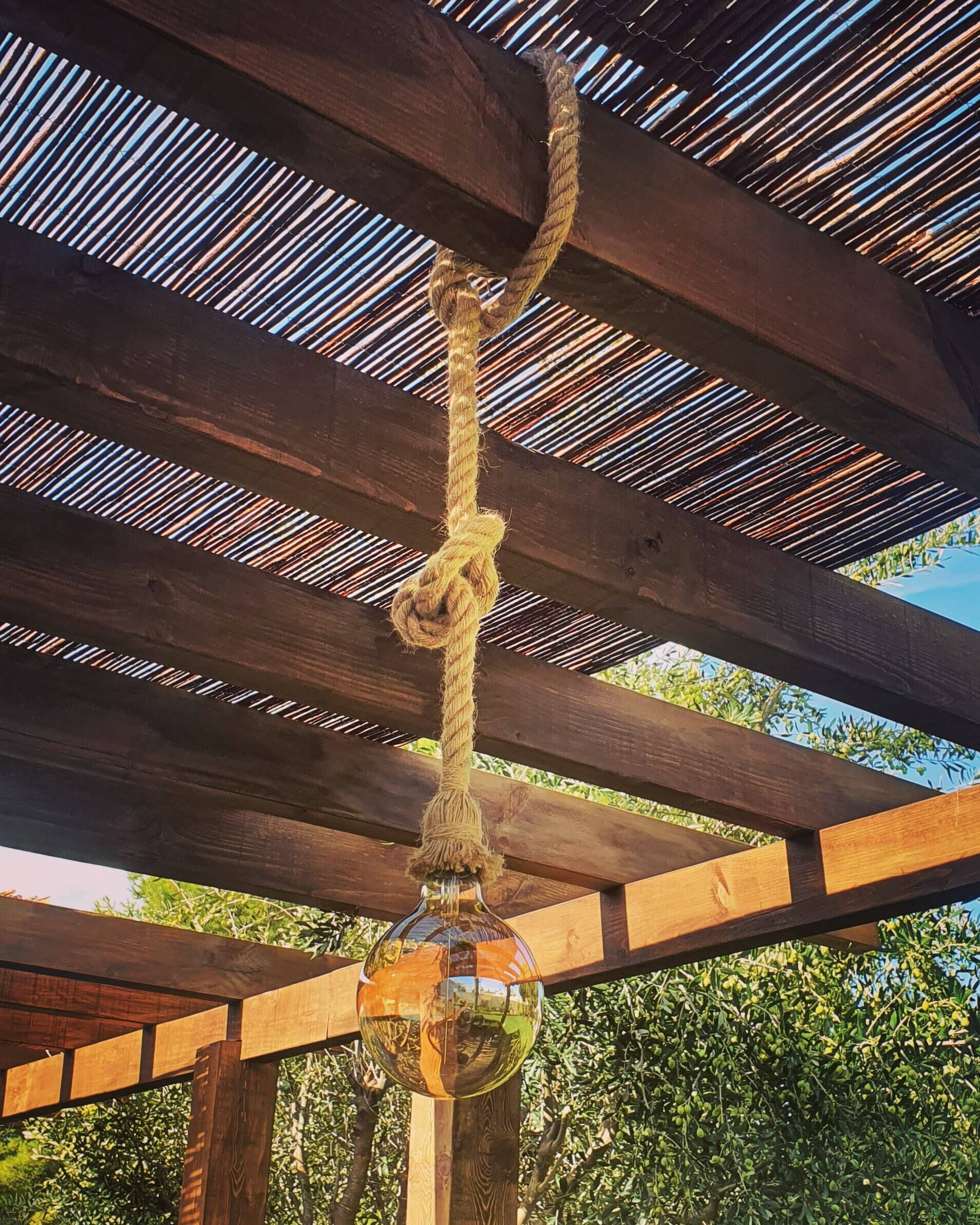 Una pérgola de madera con una cuerda colgando del techo.