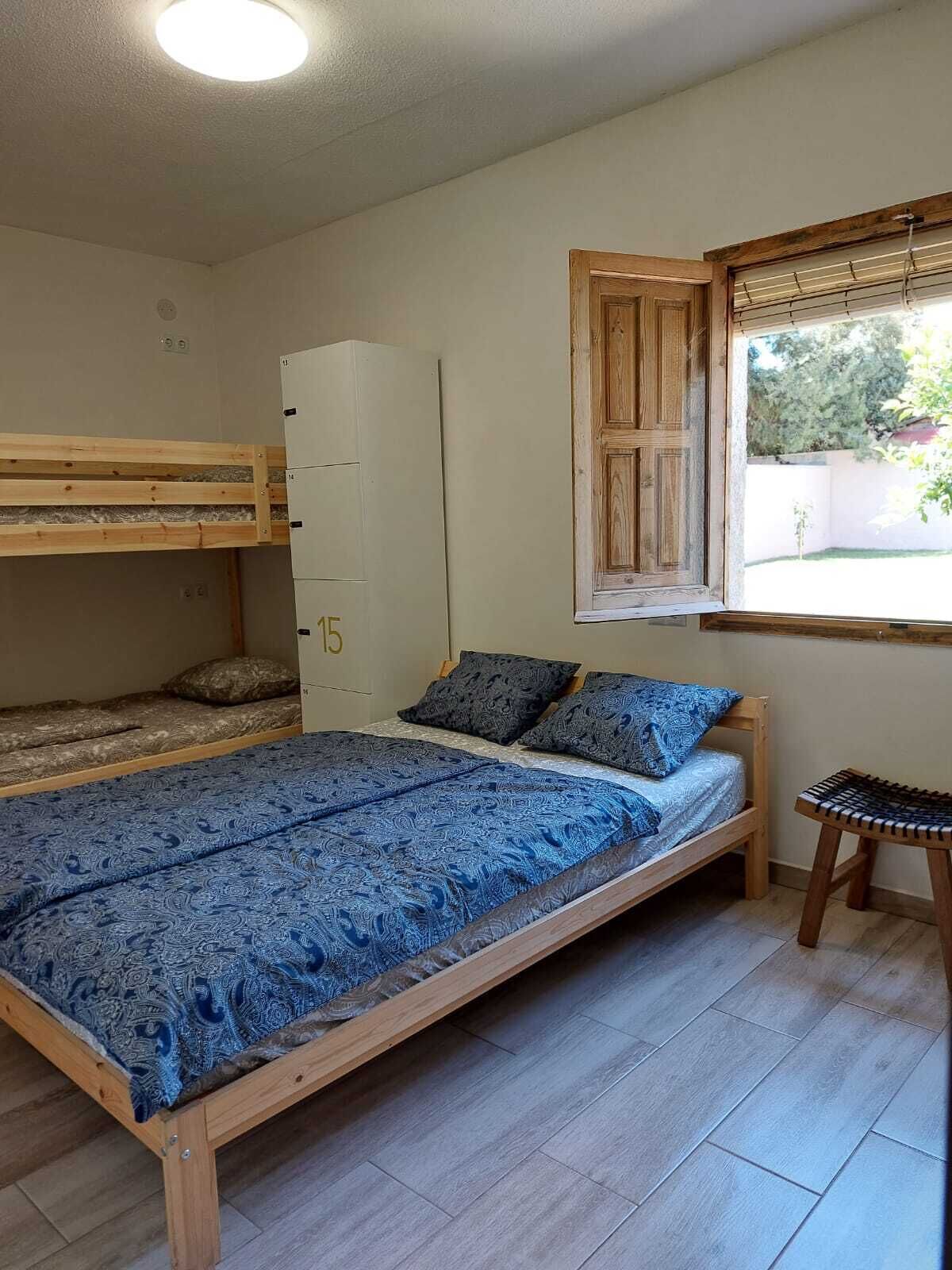 Habitación tipo dormitorio con literas, una cama individual, un armario y una ventana con vistas al exterior.
