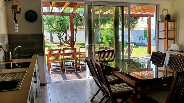 A kitchen with a dining area, a sliding glass door leading to a garden, and a chalkboard with writing on the wall. - ZENIA HOSTEL (Orihuela)