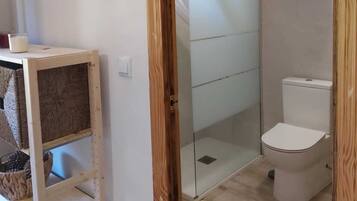 Ein Badezimmer mit Duschkabine aus Glas, Toilette und Wandheizung.