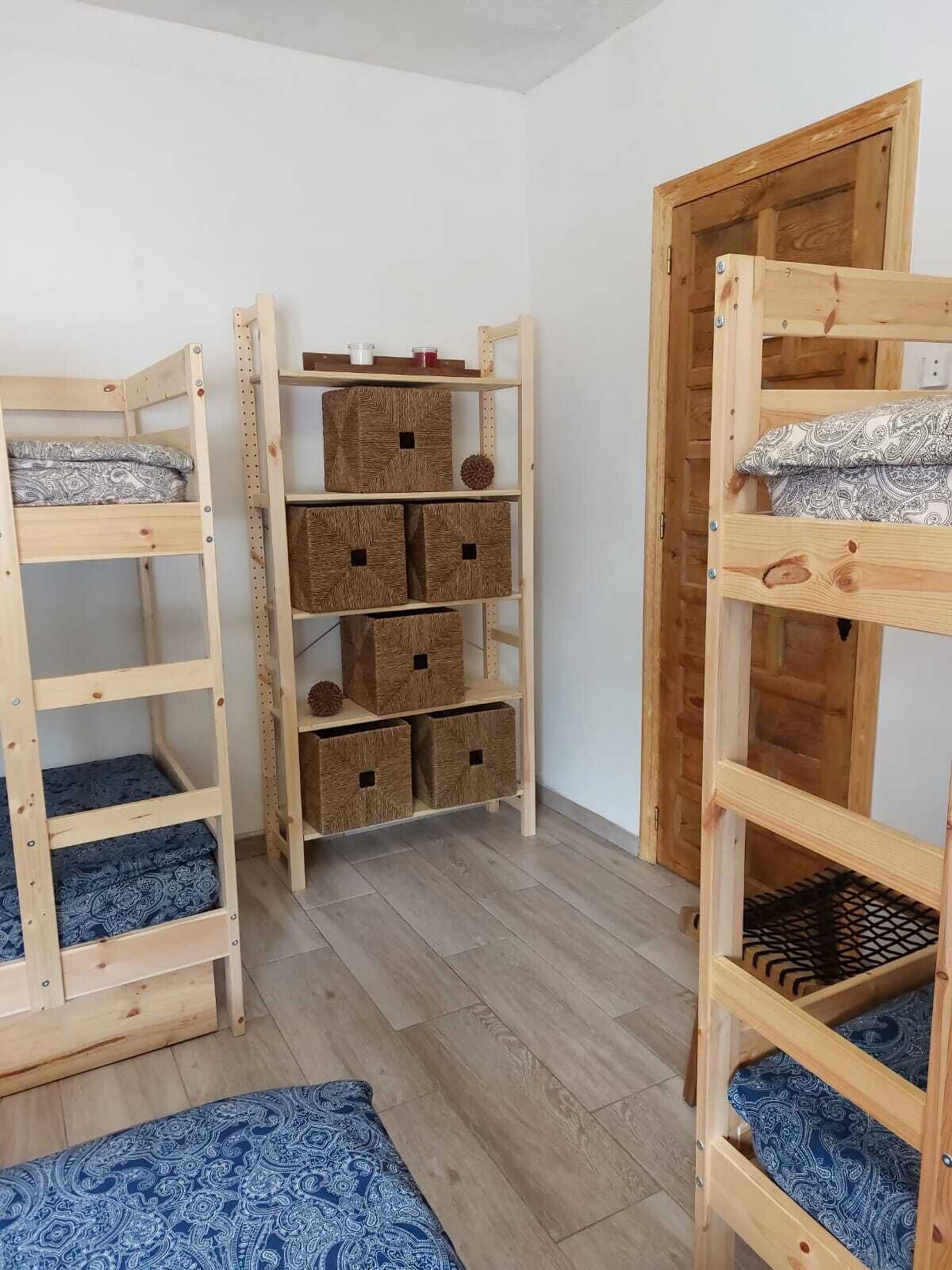 A room with two bunk beds, a wooden wardrobe, and storage boxes.