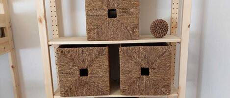Una estantería de madera con cestas tejidas en cada repisa.