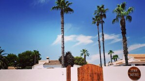A gated entrance to a property named ZENIA HOSTEL, surrounded by tall palm trees and a clear blue sky. - ZENIA HOSTEL (Orihuela)